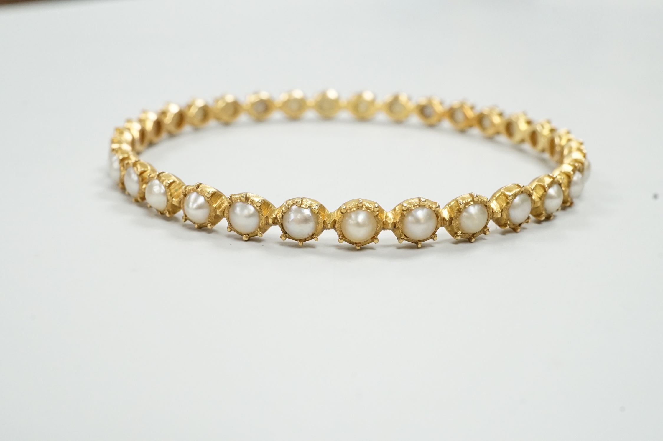 A modern yellow metal and split pearl set bangle, interior diameter approx. 58mm, gross weight 13.7 grams.